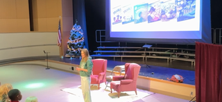 Katie Weaver giving a presentation in an auditorium with a large screen behind them.