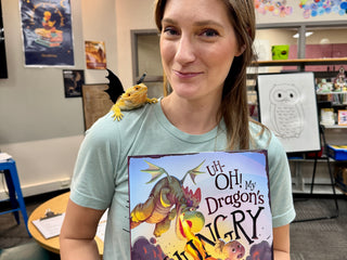 Katie Weaver holding her book titled 'Oh, My Dragon's Hungry' in a classroom setting