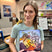 Katie Weaver holding her book titled 'Oh, My Dragon's Hungry' in a classroom setting