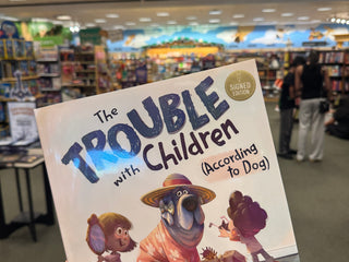 Book titled 'The Trouble with Children (According to Dog)' held in a store setting